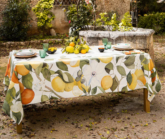 Ein rustikaler Gartentisch für vier Personen ist mit der Napking Premium Leinen Tischdecke 'Amalfi' (110 x 110 cm) eingedeckt; dekoriert mit Zitronen und Grünzeug unterstreicht sie Napkings italienische Handwerkskunst.