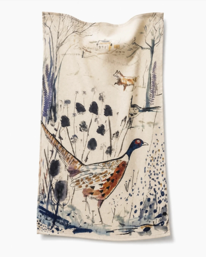 Ein cremefarbenes Küchenaccessoire von Sam Wilson, das Küchentuch „Pheasant & Fox“, wird in England aus 100 % Baumwolle hergestellt und zeigt im Vordergrund einen gemalten Fasan, umgeben von Pflanzen, einem Fuchs und Bäumen im Hintergrund – alles kunstvoll im Aquarellstil gestaltet. Dieses Geschirrtuch verleiht jeder Küche eine elegante Note.