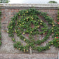 Eine Ziegelwand mit einem spiralförmig angeordneten Birnbaum und vertikalen Obstbäumen zeigt Baumschultechniken - alle tragen Früchte auf Holzspänen - im Workshop "Sommerschnitt von Gehölzen" der Königlichen Gartenakademie, Sa. 13.06.2026, 11-13 Uhr.