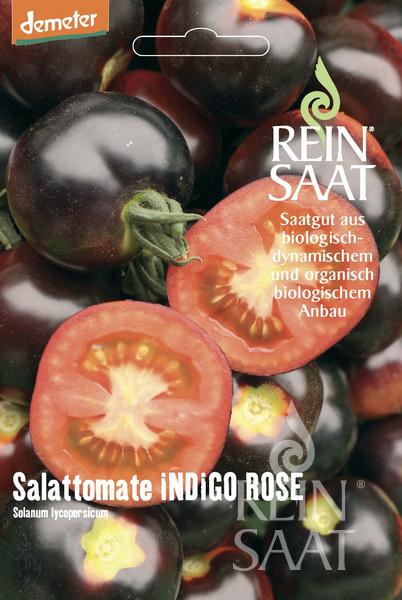 Eine ReinSaat | Salattomate 'Indigo Rose' Samenpackung von Reinsaat zeigt dunkelblau-violette Tomaten, von denen eine aufgeschnitten ist, um ihr rot-gelbes Inneres zu zeigen. Der deutsche Text weist darauf hin, dass diese Tomatenspezialität biologisch und biodynamisch angebaut wird.