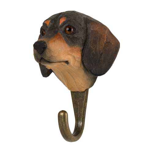 Der Wildlife Garden Handgeschnitzter Wandhaken aus Lindenholz 'Dackel' hat einen sorgfältig geschnitzten und bemalten Hundekopf mit schwarzen und braunen Felldetails sowie einen stabilen Metallhaken.