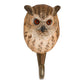 Der 'Uhu' Wandhaken von Wildlife Garden ist aus Lindenholz handgeschnitzt und zeigt einen Eulen-Kopf mit braun-beigen Federn, roten Augen und spitzen Ohren. Der Metallhaken sitzt am Halsansatz der detailreichen Figur.