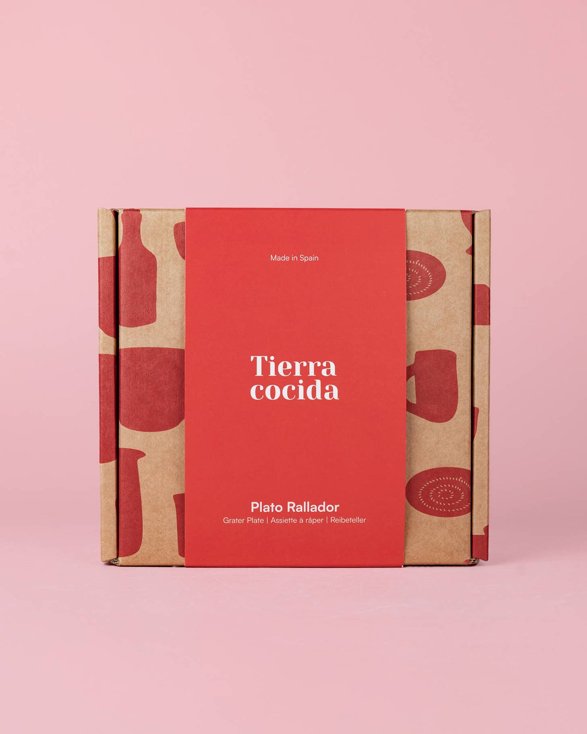 Auf einem rosa Hintergrund steht eine quadratische Schachtel mit einer roten Hülle, auf der „Alfar Tierra Cocida“ steht und die den Produktnamen „Keramikschale mit Knoblauchreibe Mittelrosa ‚Sakura‘“ trägt. Die Schachtel mit der Aufschrift „Made in Spain“ ist mit roten Illustrationen von Küchenutensilien verziert und enthält eine Keramikschale mit Knoblauchreibe – ein handbemalter spanischer Küchenhelfer, der sich perfekt für Ihre kulinarischen Bedürfnisse eignet.