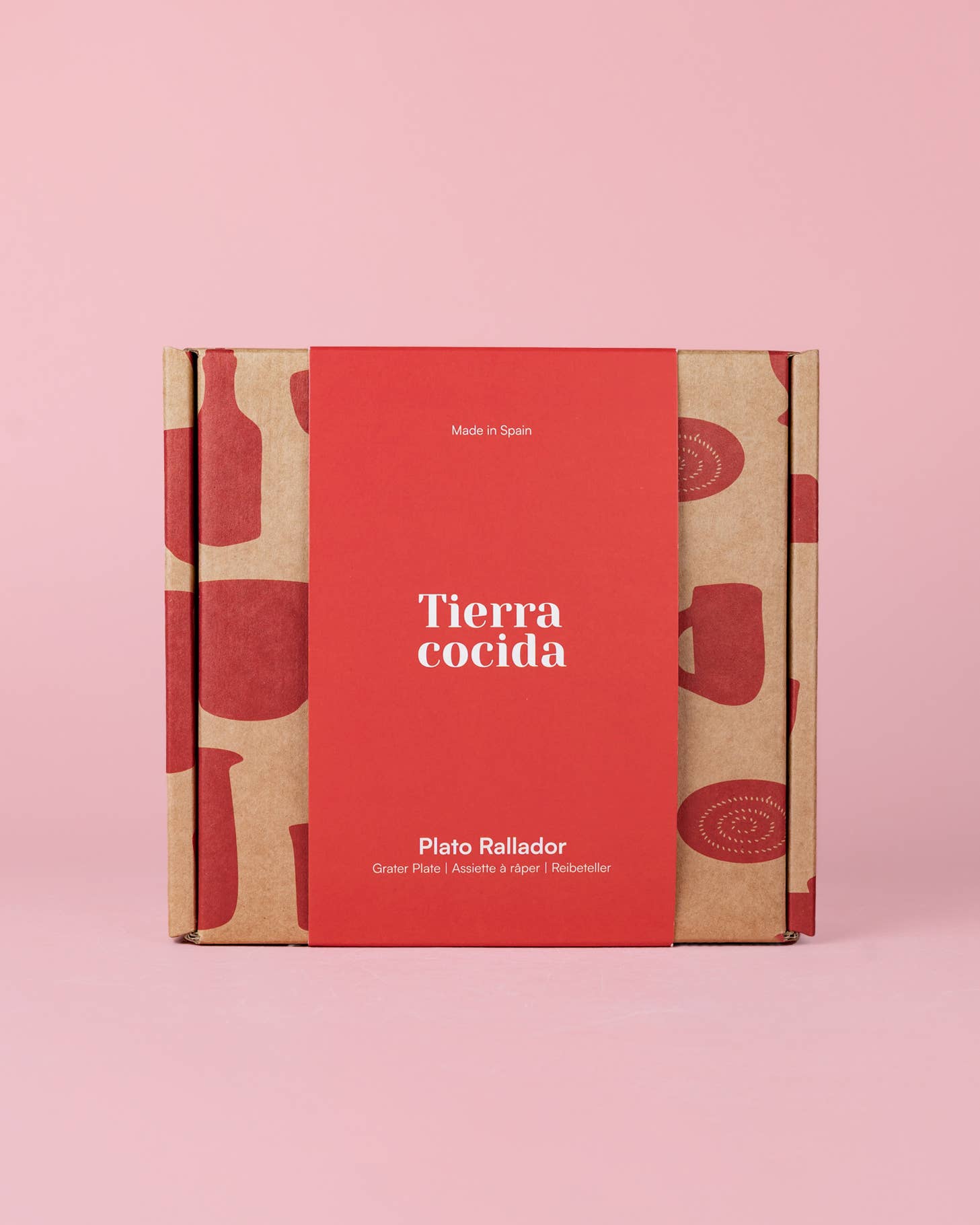 Auf einem rosa Hintergrund steht eine quadratische Schachtel mit einer roten Hülle, auf der „Alfar Tierra Cocida“ steht und die den Produktnamen „Keramikschale mit Knoblauchreibe Mittelrosa ‚Sakura‘“ trägt. Die Schachtel mit der Aufschrift „Made in Spain“ ist mit roten Illustrationen von Küchenutensilien verziert und enthält eine Keramikschale mit Knoblauchreibe – ein handbemalter spanischer Küchenhelfer, der sich perfekt für Ihre kulinarischen Bedürfnisse eignet.