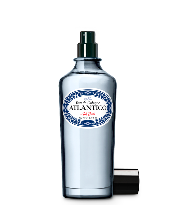 Der klare Glasflakon mit der Aufschrift Eau de Cologne | Atlântico 100 ml von Ach.Brito in blau-weißem Design mit dunklem Sprühkopf und passender Kappe erinnert an die Meeresfrische des klassischen Atlântico-Duftes.