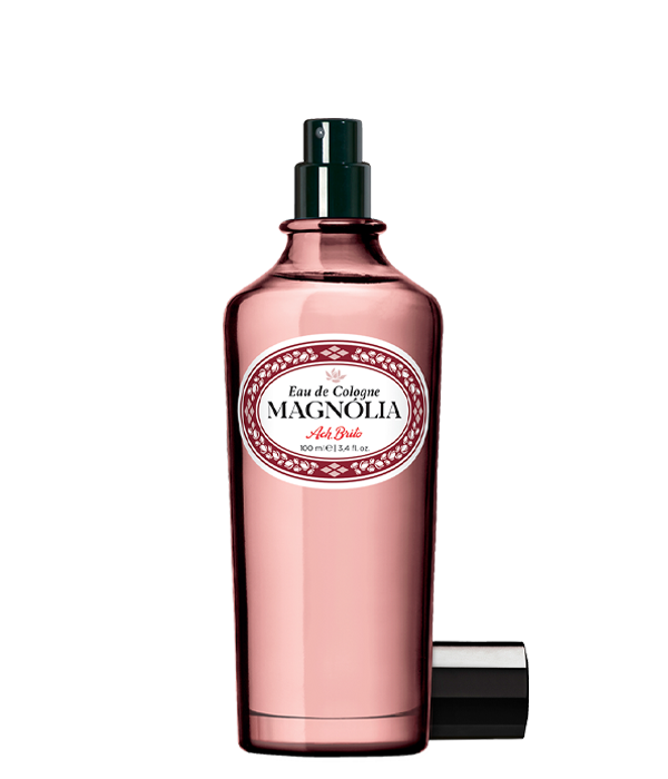 Ein rosafarbener Glasflakon von Ach.Brito Eau de Cologne | Magnolia 100 ml mit schwarzem Sprühkopf und Kappe steht auf einem weißen Hintergrund.
