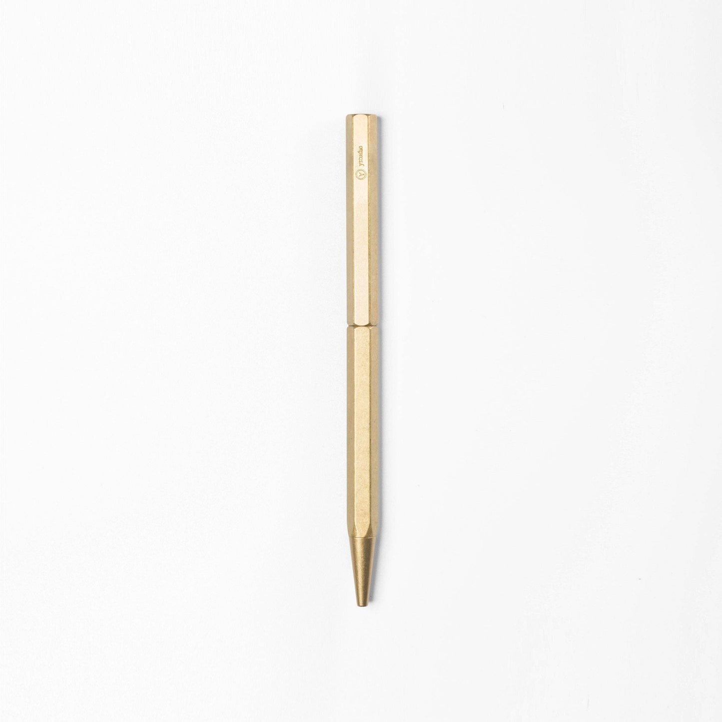 Der ENTREPÔT YSTUDIO | Klassischer Revolve Kugelschreiber Schlank in Gold, mit sechseckiger Form und minimalistischem Design, steht senkrecht auf einem schlichten weißen Hintergrund.