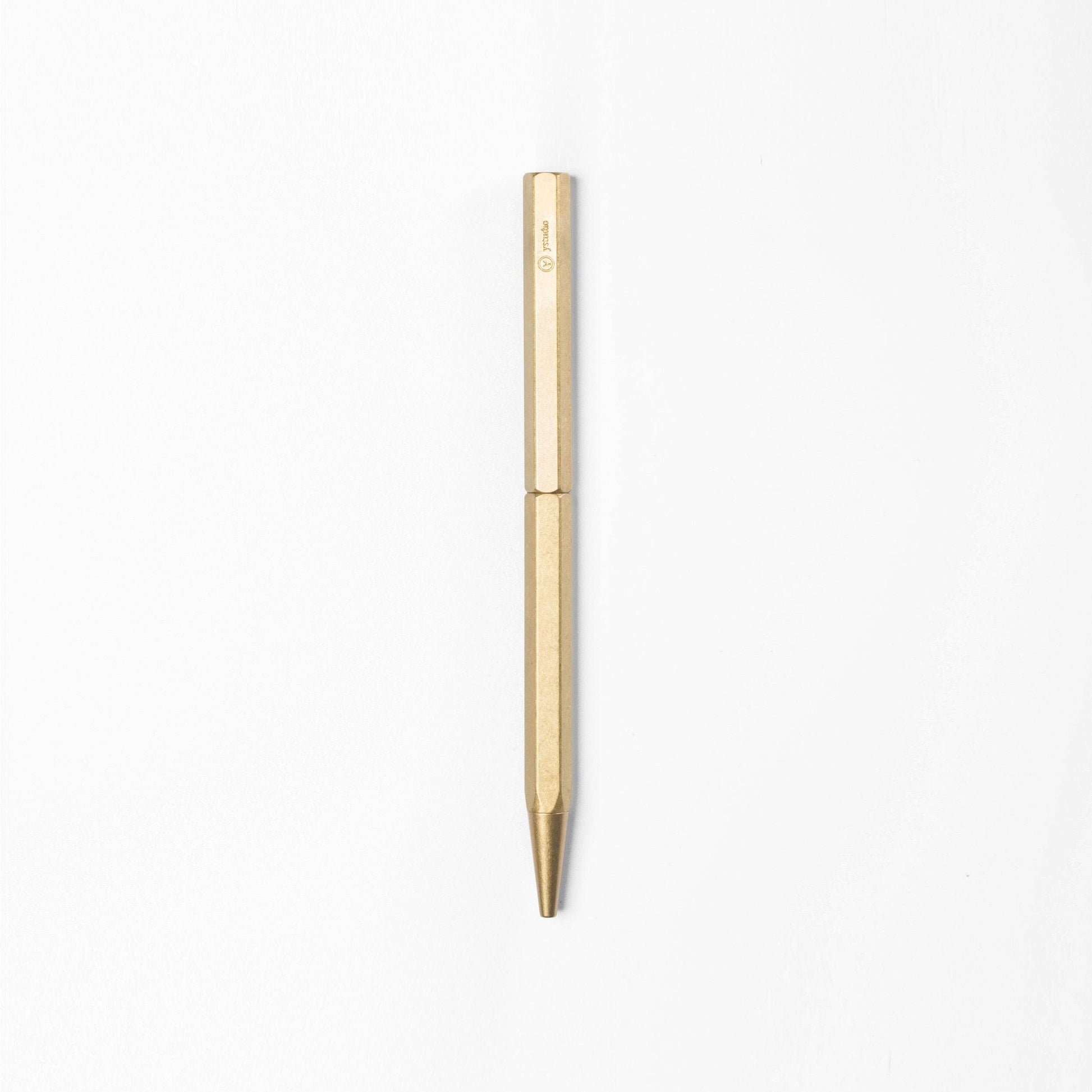 Der ENTREPÔT YSTUDIO | Klassischer Revolve Kugelschreiber Schlank in Gold, mit sechseckiger Form und minimalistischem Design, steht senkrecht auf einem schlichten weißen Hintergrund.