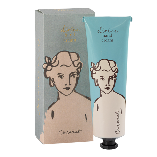 Eine blau-weiße Tube Archivist | 'Kokosnuss' Handcreme von Archivist Gallery mit der Aufschrift "göttliche Handcreme" und einem illustrierten Frauengesicht steht neben der passenden Schachtel mit demselben Design.