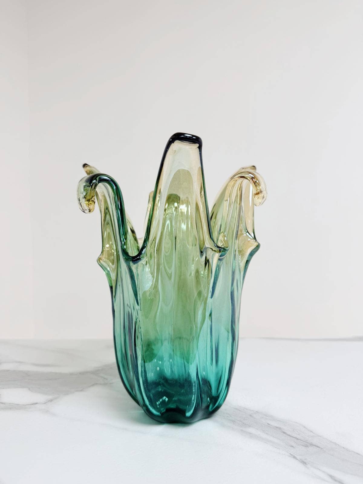 Die Murano Dream „Giusy“-Vase (H 24, Ø 18 cm) besticht als handgefertigte, mittelgroße Vase aus grünem Murano-Glas mit eleganten Farbverläufen in Grün, Gelb und Klarglas sowie durch ihre abgerundete, organische Form.