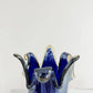 Die Murano | Große Giusy-Vase aus blauem, originalem Murano-Glas von Murano Dream mit welligen, geschwungenen Rändern steht auf weißem Marmor vor einem schlichten Hintergrund. H 32 cm, Ø 20 cm.