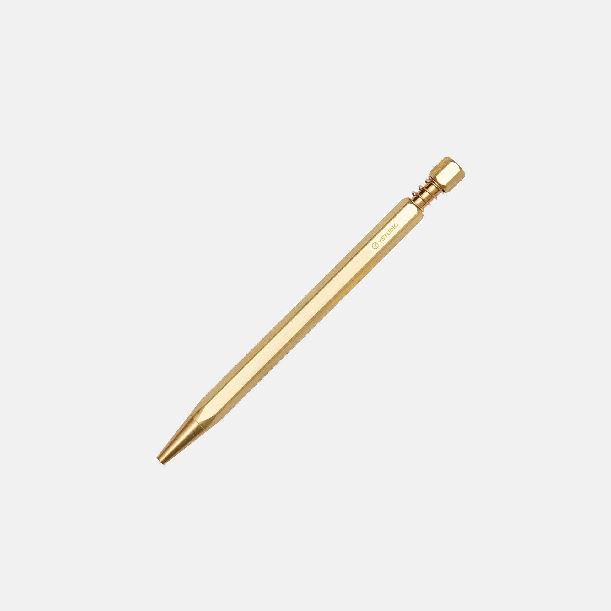 Der ENTREPÔT YSTUDIO Klassischer Revolve Kugelschreiber Feder (Messing), ein goldfarbener Metallstift mit Federkappenstruktur, spitzem Ende und sechseckigem Schraubverschluss, liegt auf weißem Hintergrund.