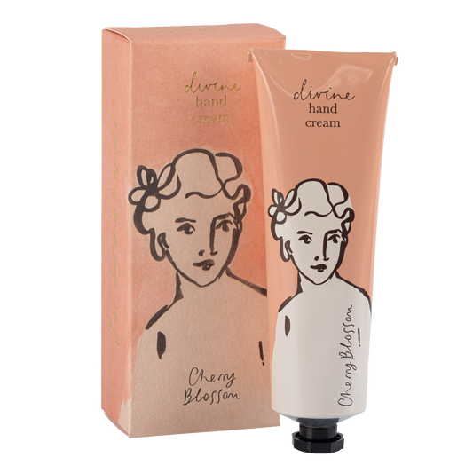 Eine pfirsichfarbene Tube Archivist | 'Kirschblüte' Handcreme von Archivist Gallery steht aufrecht mit der Kappe nach unten, zusammen mit einer passenden Schachtel. Beide zeigen eine einfache schwarze Strichzeichnung eines Frauengesichts und den Text "Cherry Blossom" (Kirschblüte).