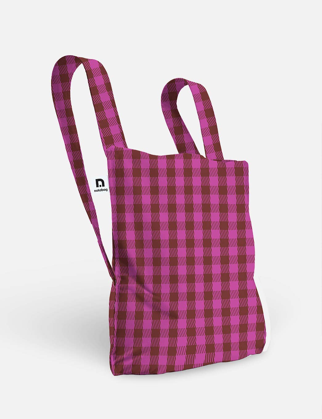 Die Notabag | Wandelbare Tasche und Rucksack „Kirsche“ von Notabag wird vor einem schlichten weißen Hintergrund präsentiert, wodurch ihr Design mit zwei Tragegriffen und das lebhafte karierte Muster in Pink und Bordeauxrot besonders gut zur Geltung kommen – diese vielseitige Tasche verbindet Funktionalität nahtlos mit modernem Stil.