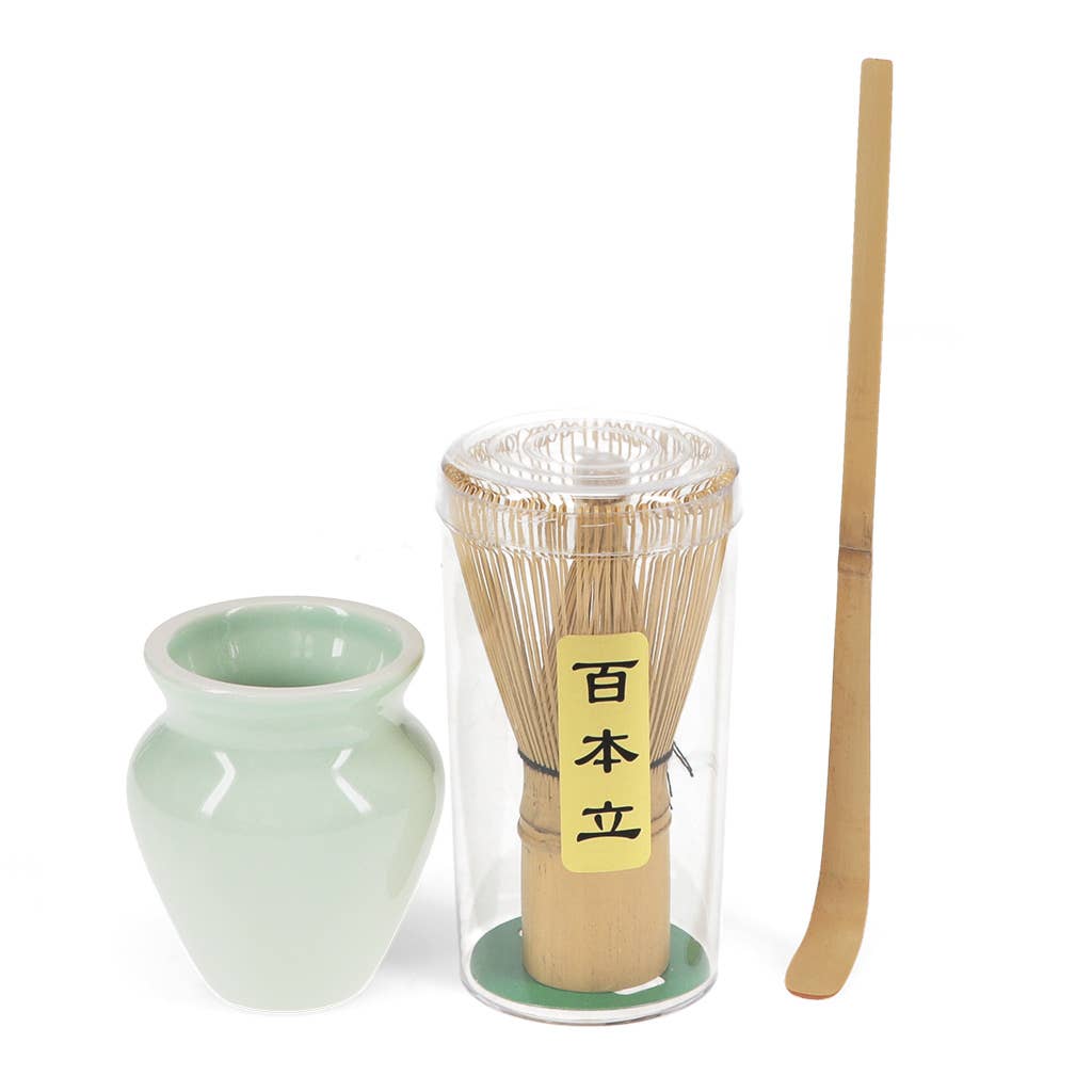 Eine hellgrüne Keramikschüssel, ein Bambus-Matcha-Besen mit Ständer und ein Bambuslöffel aus dem Rex | Handgefertigter Matcha Besen & Ständer im Set von Rex Europe sind fein säuberlich nebeneinander auf einem weißen Hintergrund angeordnet.