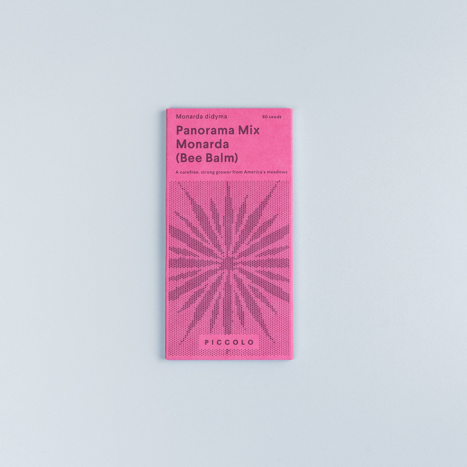 Ein rosafarbenes Saatgutpaket von Piccolo Seeds | 'Monarda Panorama-Mix' scharlachroter Bienenbalsam oder Bergamotte, mit einem geometrischen Blumenmuster, kleinem Saatgut-Info-Text und dem Markennamen Piccolo Seeds auf hellgrauem Hintergrund.