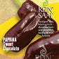 Eine Saatgutpackung von Reinsaat für Paprika 'Sweet Chocolate' (Capsicum annuum) mit drei dunkelvioletten Paprikaschoten, mit deutschem Text über biologischen und biodynamischen Anbau, mit der Aufschrift samenfest und der Marke Reinsaat.
