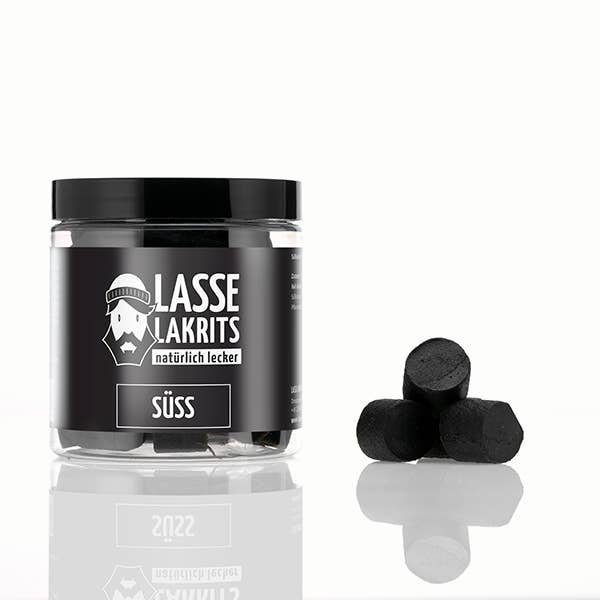 Ein klares LASSE LAKRITS | Dose Lakritz Süss natürlich lecker Glas mit schwarzem Deckel steht auf einer weissen Fläche. Daneben sind vier Stück veganes Lakritz in einer kleinen Pyramide gestapelt.