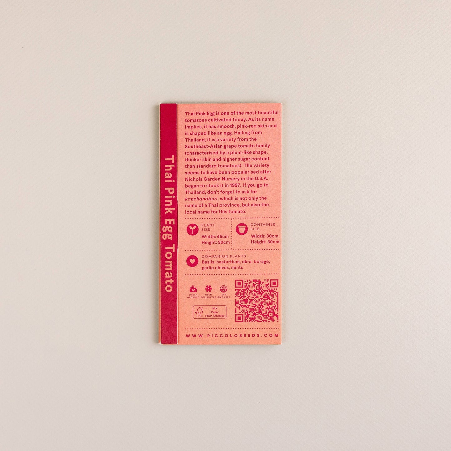 Eine Piccolo Seeds | Tomaten-Thai-rosa Ei rosa Saatgutpackung von Piccolo Seeds mit Sortenangaben, QR-Codes, Anleitungen und Icons ist auf einem schlichten hellen Hintergrund fotografiert, der diese südostasiatische Tomatenspezialität hervorhebt.