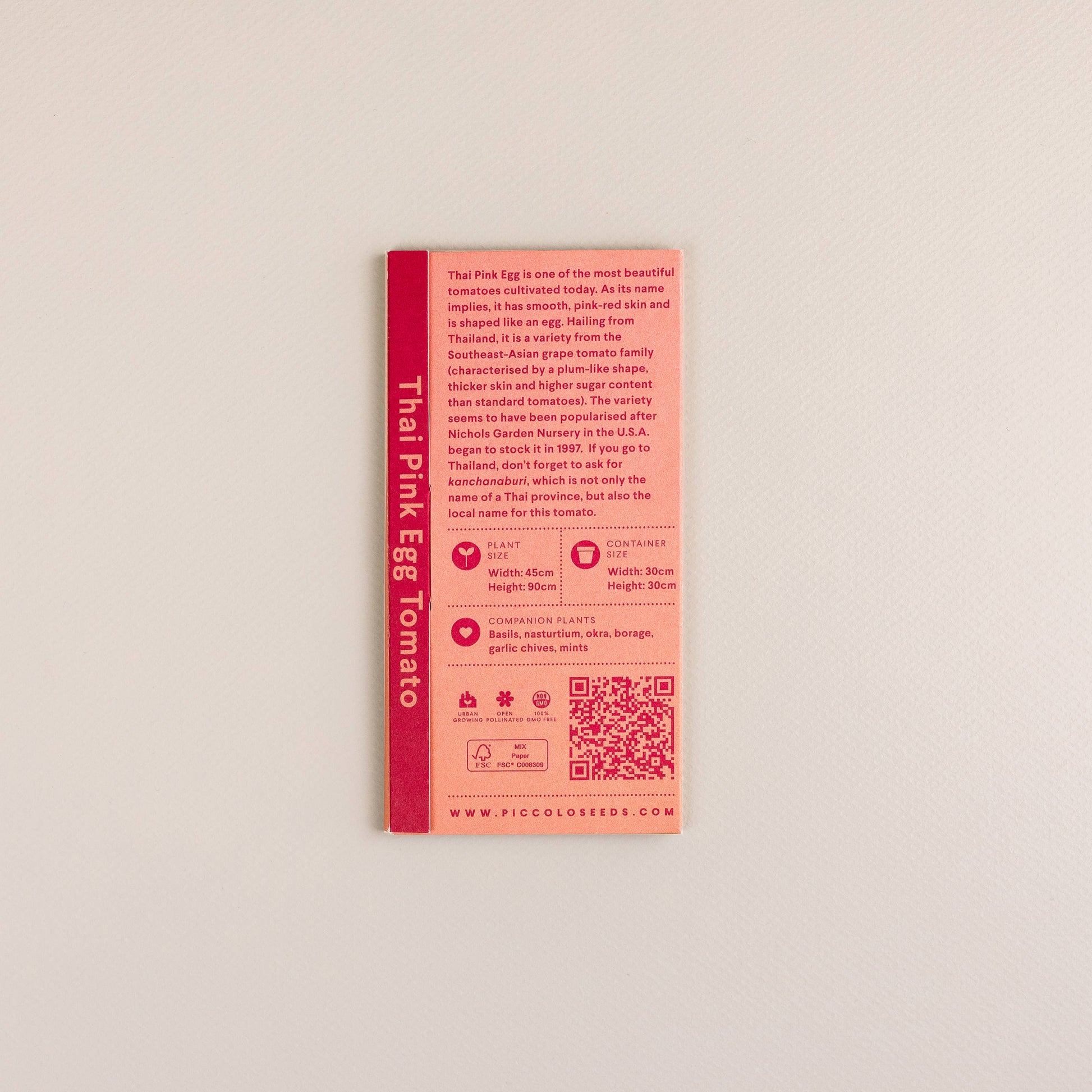 Eine Piccolo Seeds | Tomaten-Thai-rosa Ei rosa Saatgutpackung von Piccolo Seeds mit Sortenangaben, QR-Codes, Anleitungen und Icons ist auf einem schlichten hellen Hintergrund fotografiert, der diese südostasiatische Tomatenspezialität hervorhebt.
