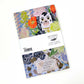 Ein farbenfrohes Notizbuch mit dem Titel "Angie Lewin | Notizbuch 'Wally Dogs and Tulpen'" von Art Angels zeigt schwarz-weiße Wally Dogs mit Tulpen sowie Markendetails auf der Rückseite.