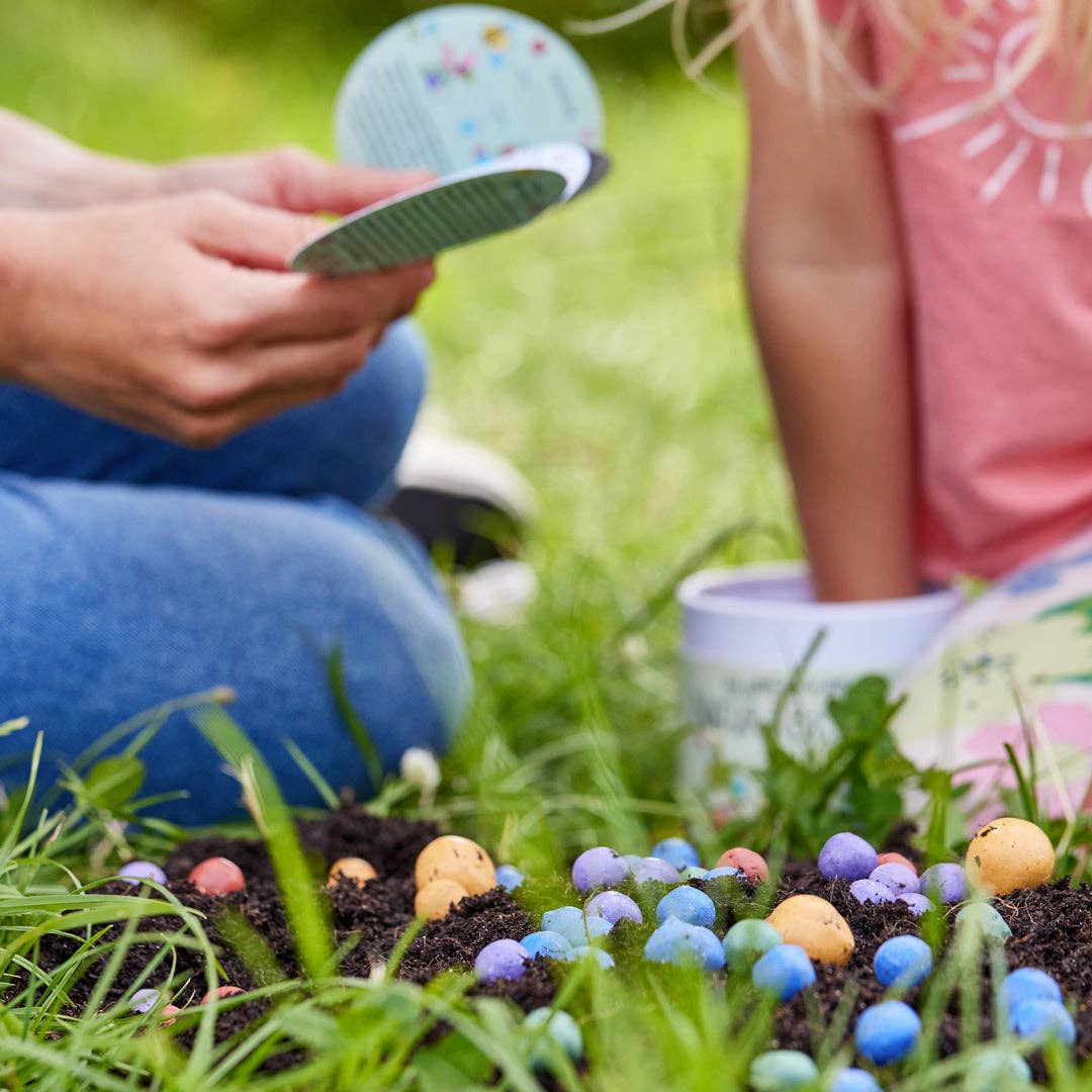 Zwei Personen sitzen auf sattgrünem Rasen und pflanzen begeistert die bunten Blumenmurmeln aus der Saatgut | Blumenmurmeln „Naturabenteuer“ 100er-Dose von Stadtgärtner in die Erde – ein echtes Naturabenteuer für Kinder! Während eine Person die Anleitung in der Hand hält, verfolgt die andere gespannt das bunte Treiben. Im Hintergrund sind praktische Saatgutbehälter zu sehen – ein nachhaltiges Geschenk von Stadtgärtner, das Kindern auf spielerische Weise Freude an der Natur vermittelt.