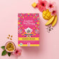 Eine Schachtel English Tea Shop | 'Mango Splash' BIO 20 Teebeutel wird mit Hibiskusblüten, Mangoscheiben, Passionsfrucht, Teeblättern und einem Teebeutel auf pastellrosa präsentiert - ideal für exotische Eistee- oder Früchtetee-Fans.