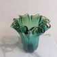 Die „Murano Dream Große ‚Fazzoletto‘“-Vase aus grünem Murano-Glas (H 32, Ø 24 cm) mit gewelltem Rand steht auf einer weißen Marmorplatte vor hellem Hintergrund.