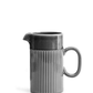 Eine glänzende dunkelgraue Keramik-Kaffeekanne (1 l) der Sagaform GmbH mit vertikalen Rillen auf der unteren Hälfte, einem geschwungenen Henkel auf der rechten Seite und einem Ausguss auf der linken Seite, dargestellt vor einem schlichten weißen Hintergrund. Inspiriert vom Sagaform Coffee & More Design.