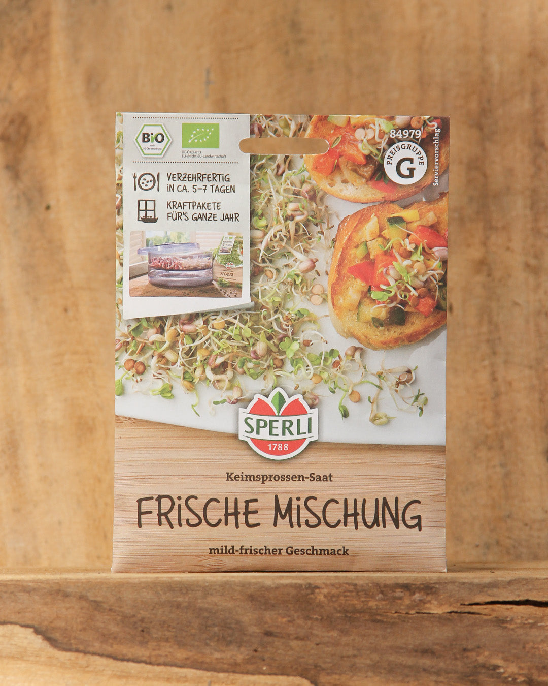 Eine Packung Sperli's | Bio Keimsprossen Saatgut 'Frische Mischung' ist auf Holz ausgestellt und zeigt frische Sprossen und Mahlzeiten. Die Verpackung hebt die Bio-Saatgut-Zertifizierung und eine schnelle Keimzeit hervor.