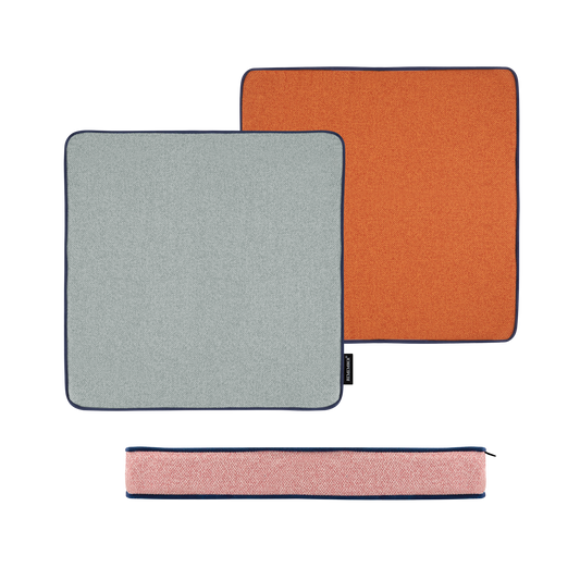 Zwei quadratische Remember Sitzkissen 'Peanut' (40 x 40 x 5 cm) in Hellgrau und Orange mit dunklem Rand sind nebeneinander abgebildet. Darunter befindet sich ein schmaler rosa Stoffbeutel mit Reißverschluss - alles auf weißem Hintergrund.