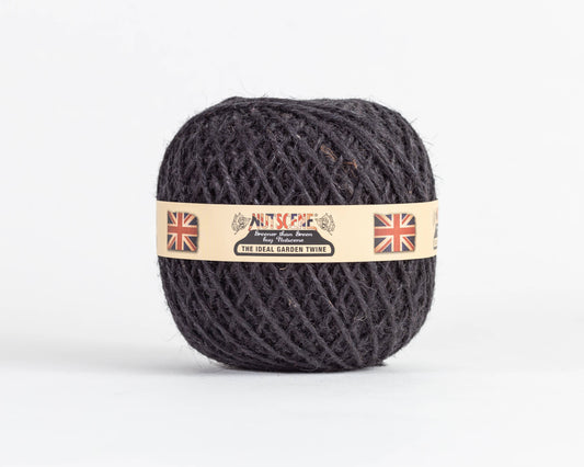 Ein Knäuel dunkler Gartenschnur, „Nutscene | Heritage Jutegarn“ in Schwarz, 130 m, von Nutscene Twines Ltd, mit einem beigen Etikett, auf dem zwei Union-Jack-Flaggen sowie die Aufschriften „Nutscene“ und „The Ideal Garden Twine“ vor einem schlichten weißen Hintergrund abgebildet sind.
