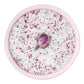 In einer rosafarbenen Schale befindet sich das Meersalz Fleur de Sel La Vie en Rose" von Sal de Ibiza, das mit Rosenblättern vermengt und in der Mitte mit einer einzelnen getrockneten Rosenknospe gekrönt ist.