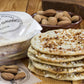 Ein Stapel „Viani '6 Tortas de Almendras‘“ – Gebäck mit Olivenöl und Mandeln (210 g), bestreut mit Zucker und gehackten Mandeln – liegt neben ganzen Mandeln und der Viani-Verpackung auf einem Holztisch.