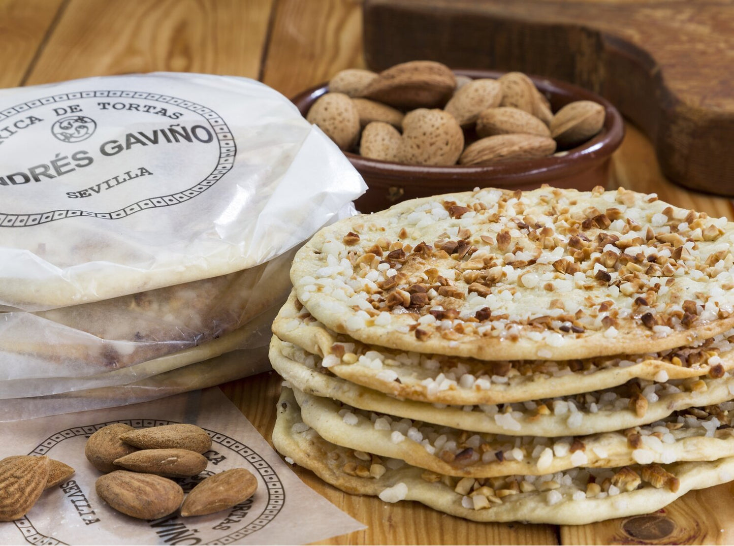 Ein Stapel „Viani '6 Tortas de Almendras‘“ – Gebäck mit Olivenöl und Mandeln (210 g), bestreut mit Zucker und gehackten Mandeln – liegt neben ganzen Mandeln und der Viani-Verpackung auf einem Holztisch.