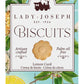 Lady Joseph | Zitronen-Curd-Kekse, 100 g, werden in einer wunderschön gestalteten Schachtel geliefert, die mit einer Vintage-Illustration einer Frau verziert ist, die auf einem Kolibri reitet, umgeben von leuchtend gelben Zitronen und floralen Details. Die auffällige Verpackung hebt hervor, dass diese Kekse handwerklich hergestellt und palmölfrei sind – diese Informationen sind auf Englisch, Spanisch und Französisch angegeben. Diese Zitronenkekse sind perfekt für alle, die Gebäck aus Spanien schätzen, und