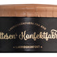 Eine schwarz-braune Dose mit goldfarbener Aufschrift „Hattesens Lakritzkonfekt“ unter einem Deckel mit Kunstlederstruktur – ideal zur Präsentation des exquisiten Hattesens Lakritzkonfekt | Lakritz, Schokolade & Mokka 125 g.