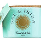 Ein türkisfarbenes Keramikgefäß mit „Fleur de Sel“-Meersalz von Sal de Ibiza, 150 g, verziert mit einem goldenen Sonnenlogo, einem Korkdeckel, einem beigefügten Löffel und einem passenden Etikett. Unterhalb der Sonne erscheint der Schriftzug „Cristal de la Vida Ibiza“, der das hochwertige Fleur de Sel-Meersalz hervorhebt.