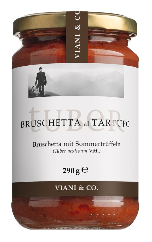 Ein Glas „Viani Bruschetta mit Sommertrüffeln“ (290 g) mit einem weißen Etikett, auf dem ein Schwarz-Weiß-Foto einer Person zu sehen ist, sowie einem Text, der das Produkt als „ein italienischer Aufstrich“ beschreibt.