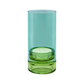 Das „Remember | Windlicht ‚Lys’ Sky“ von Remember ist ein zylindrisches Windlicht aus Glas, dessen obere Hälfte in transparentem Aquablau gehalten ist und dessen Sockel aus durchgefärbtem Grün besteht – elegant in Szene gesetzt vor einem weißen Hintergrund.