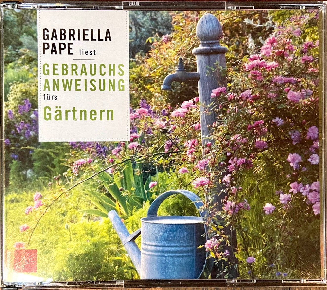 Eine üppige Gartenszene zeigt eine Gießkanne an einer alten Pumpe inmitten rosa Blüten. Text: Gabriella Pape präsentiert das Hörbuch "Gebrauchsanweisung fürs Gärtnern | Praxis & Tipps".