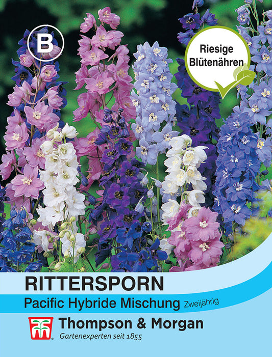 Hohe Rispen mit rosa, lila, blauen und weißen Ritterspornblüten und grünen Blättern. Etikett: "Thompson & Morgan | Rittersporn Pacific Hybride Mischung" von Thompson und Morgan. Auf dem gelben Kreis steht "Riesige Blütenähren.