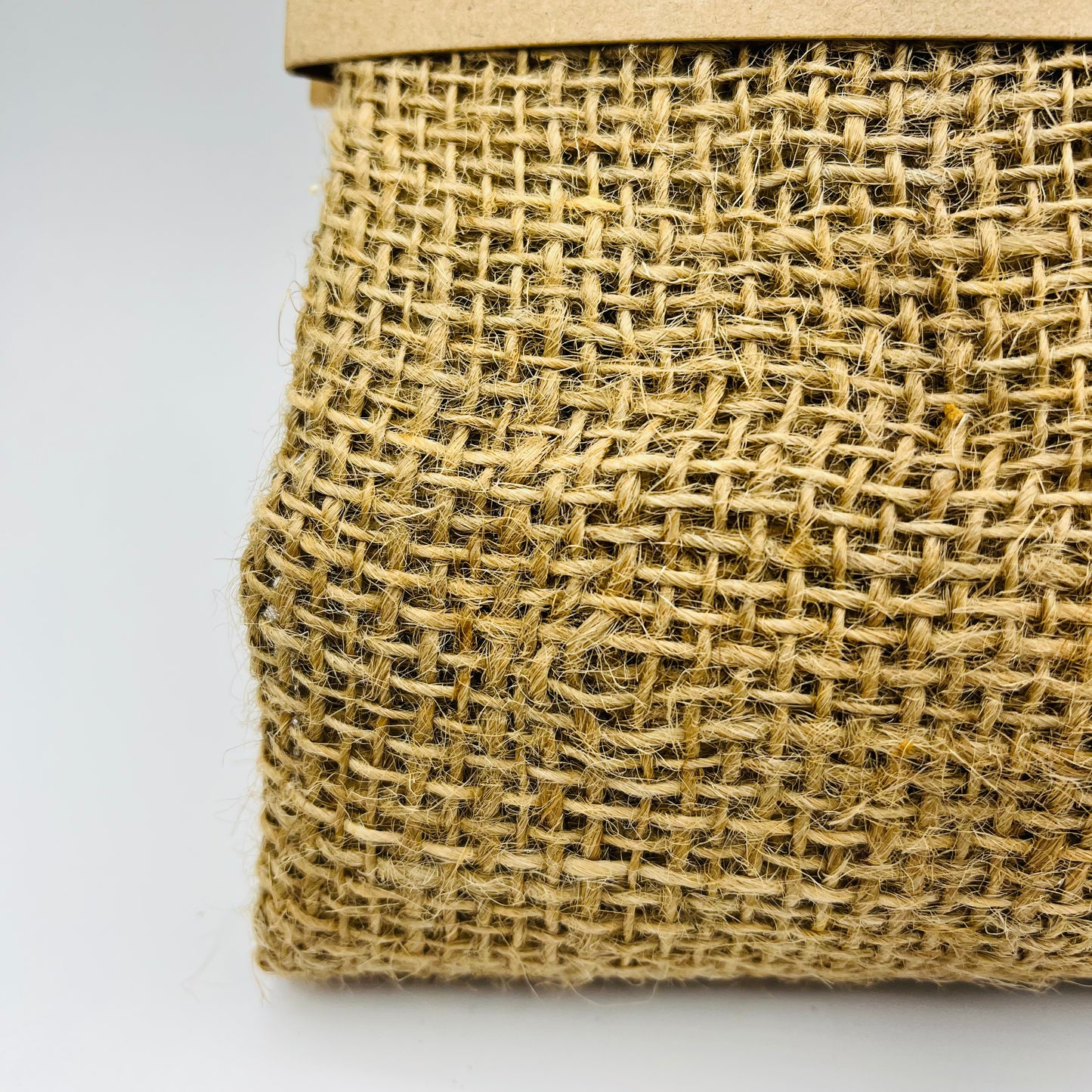 Eine Nahaufnahme der Esschert Jute-Frostschutzabdeckung S zeigt die gewebte Naturfaserstruktur und den Papprand - perfekt als biologisch abbaubare Pflanzenabdeckung - vor einem schlichten, hellen Hintergrund.