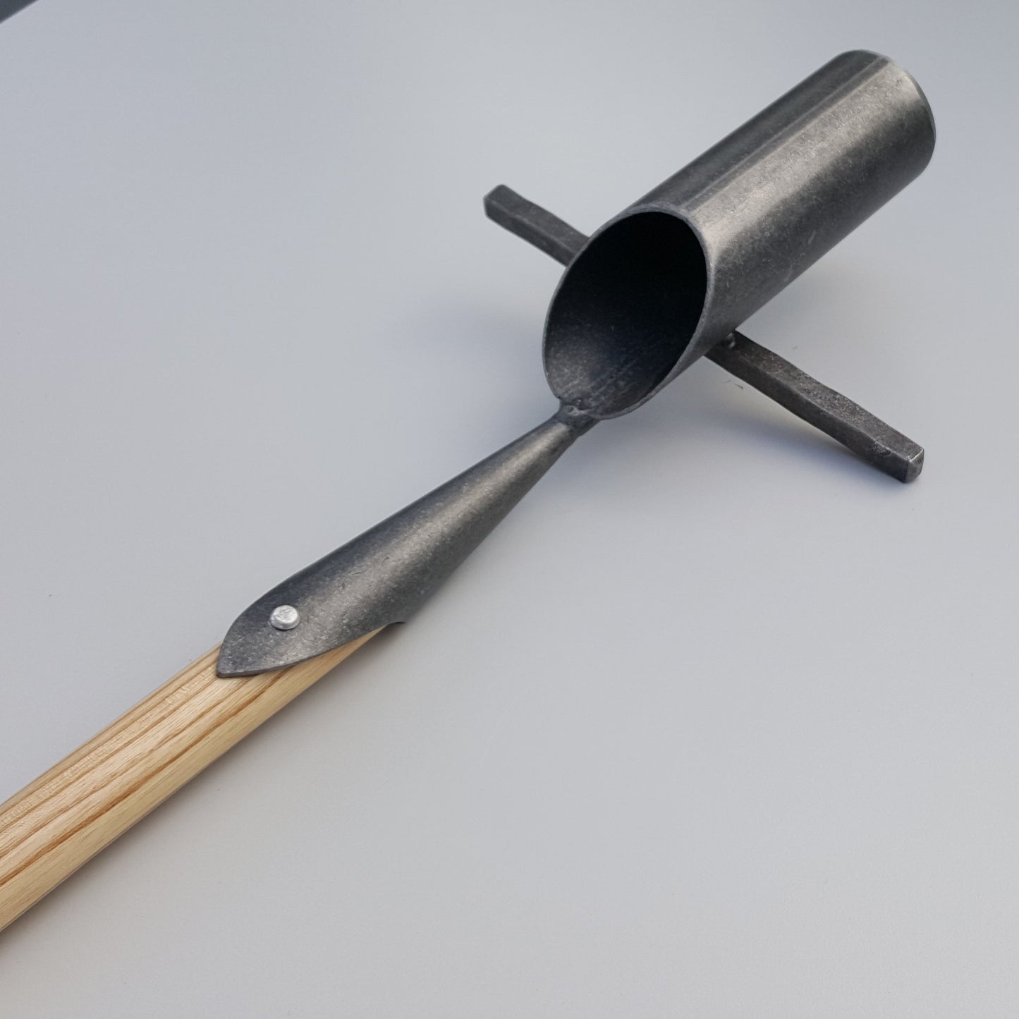 Der Krumpholz | Zwiebelpflanzer 1349 mit zylindrischer Metallschaufel, Kreuzgriff und Eschen-T-Stiel-Holzstiel ruht auf einer hellgrauen Oberfläche - perfekt für Bodenproben oder das Pflanzen von Blumenzwiebeln.