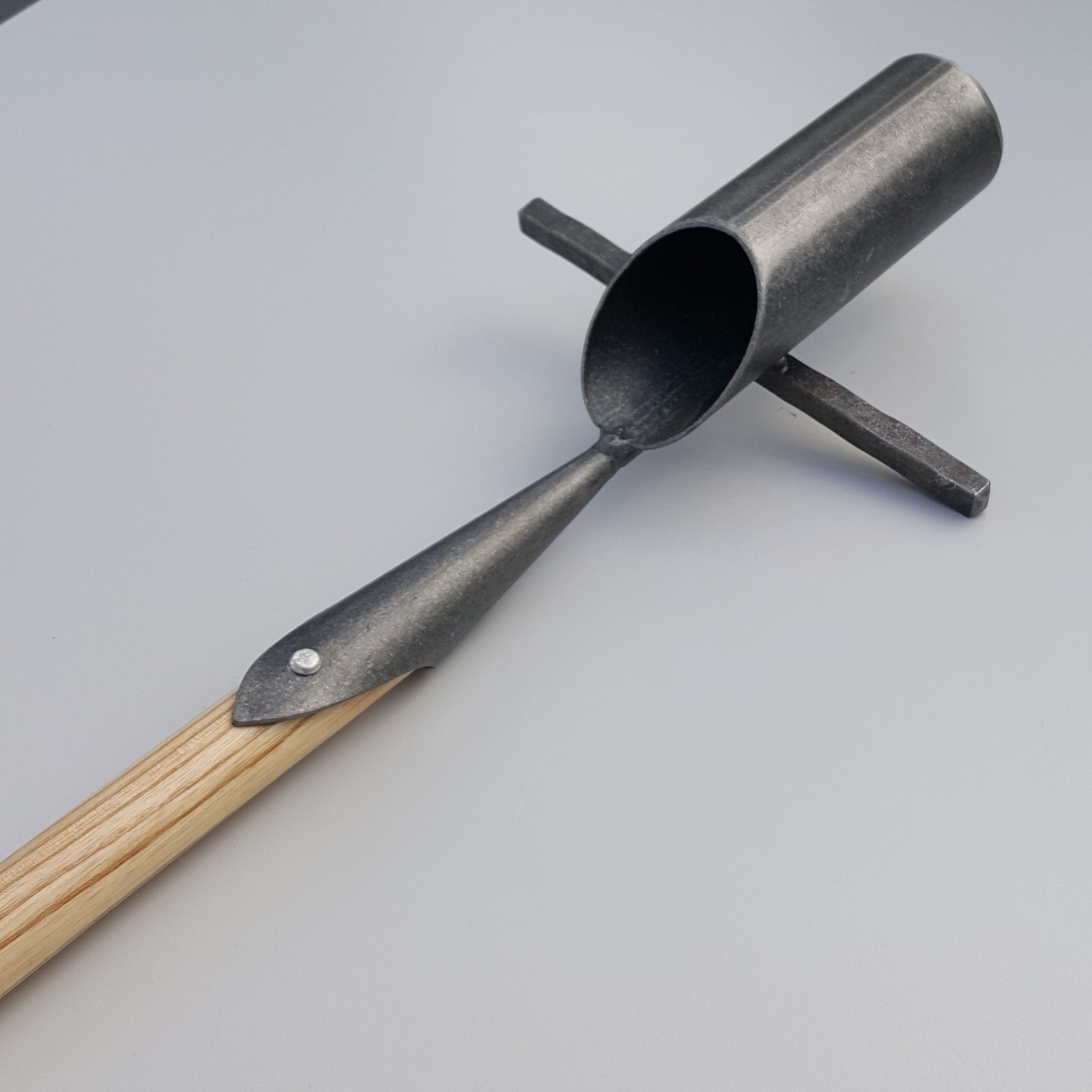 Der Krumpholz | Zwiebelpflanzer 1349 mit zylindrischer Metallschaufel, Kreuzgriff und Eschen-T-Stiel-Holzstiel ruht auf einer hellgrauen Oberfläche - perfekt für Bodenproben oder das Pflanzen von Blumenzwiebeln.