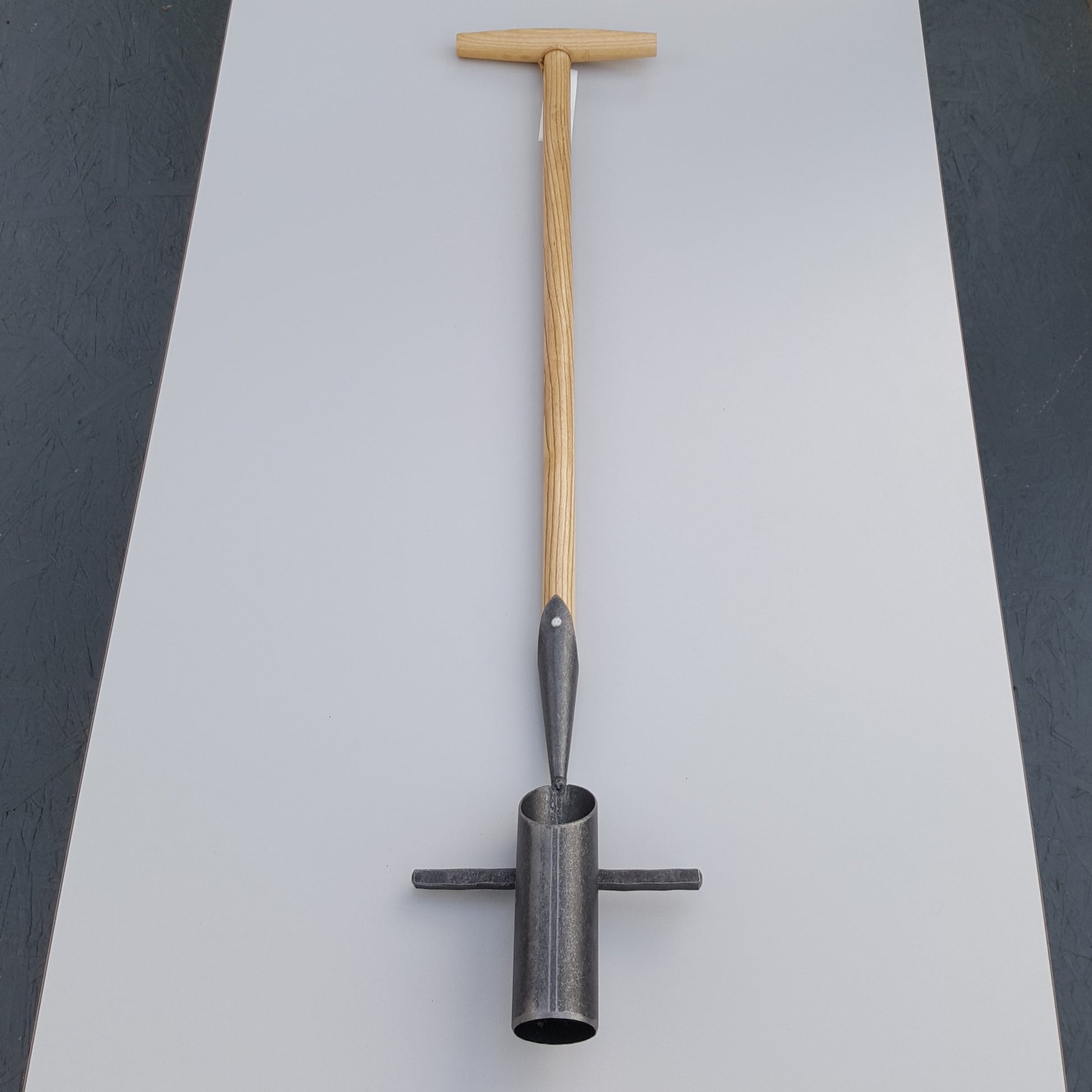 Der Krumpholz | Zwiebelpflanzer 1349 mit Eschen-T-Stiel und metallener Zylinderspitze von Krumpholz liegt auf einer grauen Fläche.